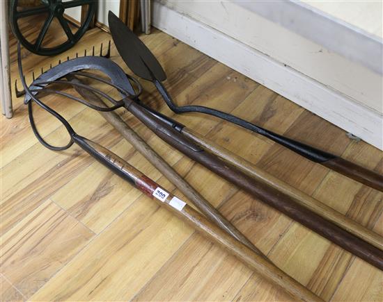 A collection of 19th century hay and pitch forks and a long handled sickle